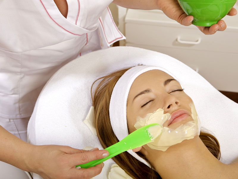 Young woman getting beauty skin mask treatment on her face with